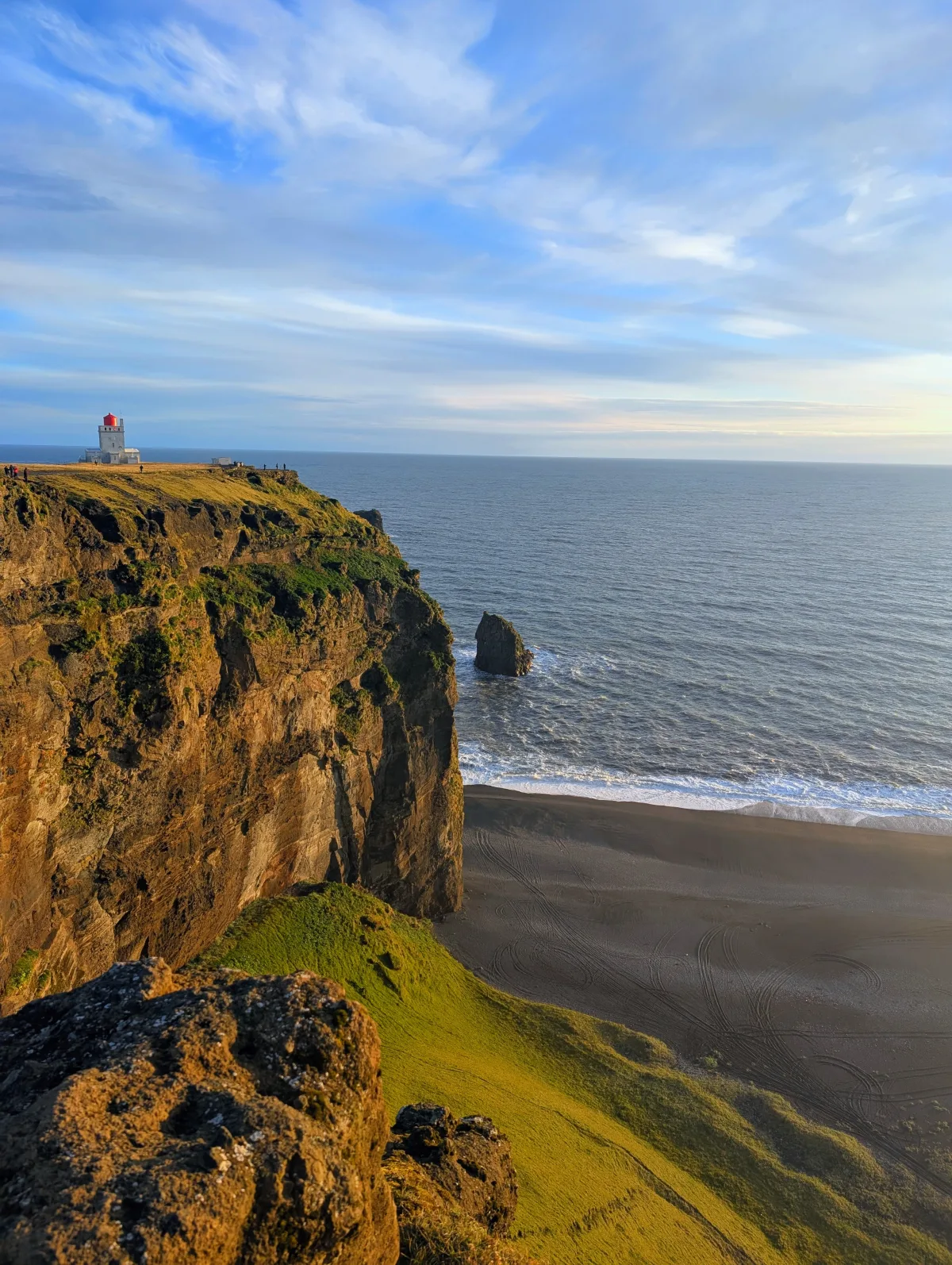 Lighthouse, coastal cliffs, and black sand beach at Dyrhólaey, Iceland.
